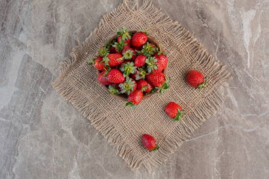 Mermer arka planda bir kumaş parçasında sulu çilek kasesi. Yüksek kalite fotoğraf