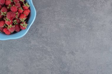 Mavi kasede bir sürü kırmızı ahududu. Yüksek kalite fotoğraf