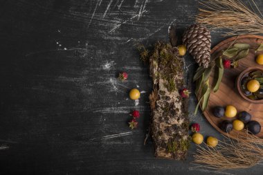 Lezzetli erik ve ahududu manzarası. Koyu arkaplanda ahşap elementler var.