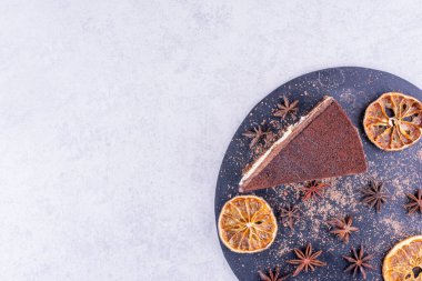 Koyu tahtada karanfil ve portakal dilimleri olan bir dilim çikolatalı pasta. Yüksek kalite fotoğraf