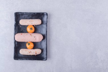 Kaynamış sosis ve siyah tabakta vişneli domates. Yüksek kalite fotoğraf