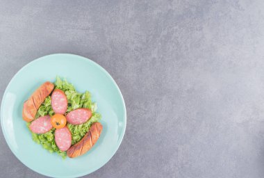 Pişmiş sosis ve dilimlenmiş sosis tabakta, mermer arka planda. Yüksek kalite fotoğraf