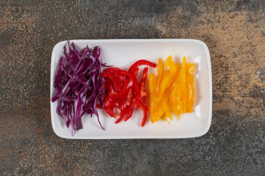 Dilimlenmiş kırmızı ve sarı biber seti, beyaz tabakta mor lahana. Yüksek kalite fotoğraf