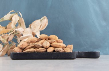 Yaprakların yanında mermer zemin üzerinde bir tepsi badem. Yüksek kalite fotoğraf