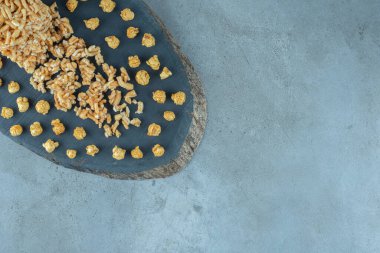 Mermer zemin üzerinde ahşap bir tahta üzerinde karamel kaplı abur cubur düzeneği. Yüksek kalite fotoğraf