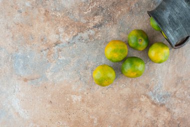 Mermer zemin üzerinde ekşi mandalinalar olan antik bir fincan. Yüksek kalite fotoğraf