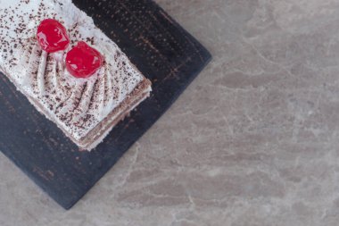 Kremalı, vişneli ve kakao tozlu küçük pasta dilimi mermer zemin üzerinde. Yüksek kalite fotoğraf