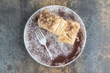 İki dilim Napolyon keki ve kakao tozu içeren beyaz bir tabak. Yüksek kalite fotoğraf