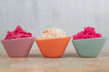 Mermer masada üç kase kırmızı ve beyaz lahana turşusu. Yüksek kalite fotoğraf