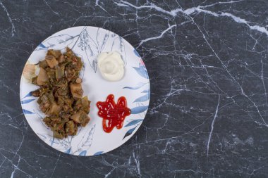 Ketçaplı marine edilmiş sebze ve beyaz tabakta yoğurt.