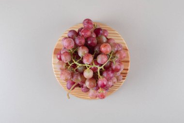 Ahşap bir tabakta mermer zemin üzerinde kırmızı üzüm kümeleri. Yüksek kalite fotoğraf