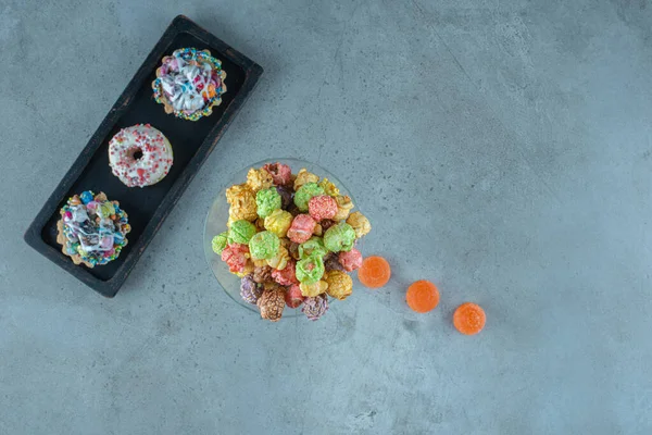 大理石の背景にドーナツ ポップコーン カップケーキやマーメレードと砂糖漬けのスナックの配置 高品質の写真 — ストック写真