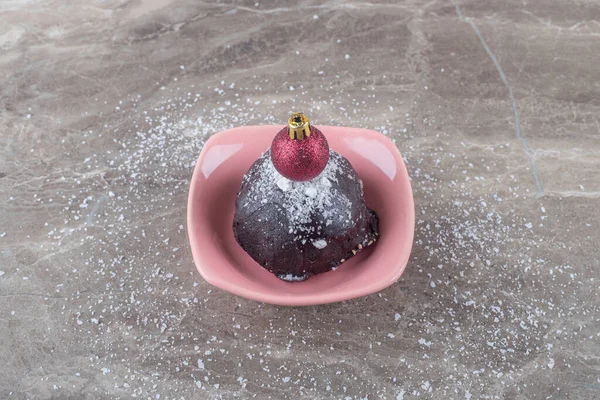 Christmas bauble on top of a chocolate coated cake in a bowl on marble background. High quality photo