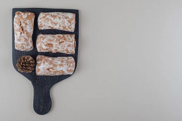 大理石の背景に板にクッキーの包装と松のコーン 高品質の写真 — ストック写真