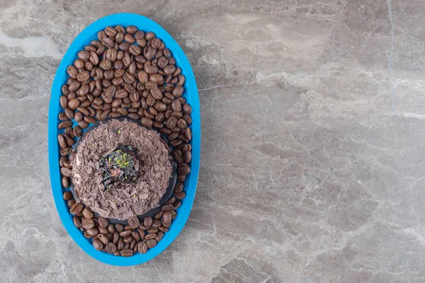 Chocolate cake on a platter full of coffee beans on marble background. High quality photo