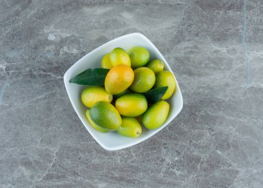 Bir kase olgunlaşmamış kumkat, mermer arka planda. Yüksek kalite fotoğraf