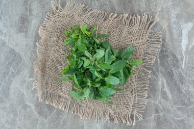 Mermer arkaplanda bir parça kumaşın üzerinde bir avuç dolusu nane yaprağı. Yüksek kalite fotoğraf