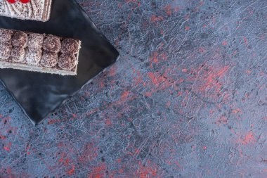 Kremalı pasta dilimleri soyut arka planda siyah bir tabakta. Yüksek kalite fotoğraf