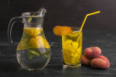 Bir bardak taze limonata ve koyu arkaplanda şeftali suyu.