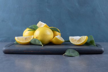 Gri tahta üzerinde taze limon ve dilimlerin fotoğrafını çek. Yüksek kalite fotoğraf