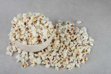 Aşırı dolu beyaz kase mermer arka planda patlamış mısır yığınının yanında. Yüksek kalite fotoğraf