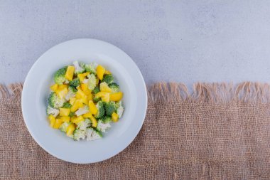 Doğranmış brokoli, karnabahar ve sarı dolma biber mermer arka planda salataya karıştırılmış. Yüksek kalite fotoğraf