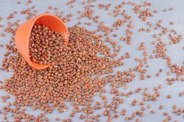 Turuncu kase mermer arka plandaki kırmızı fasulye yığınının üzerine düştü. Yüksek kalite fotoğraf