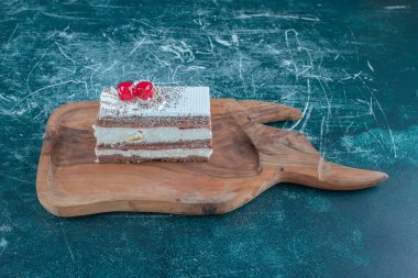 Kakao tozu ve kiraz sosu mavi arka plandaki tahta bir tahtanın üzerinde dilimlenmiş. Yüksek kalite fotoğraf