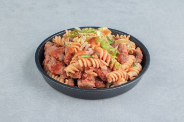 İçinde otlar ve sarmal makarna olan siyah bir tabak. Yüksek kalite fotoğraf