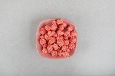 Küçük patlamış mısır yığını mermer arka planda pembe bir kaseye doldurulmuş. Yüksek kalite fotoğraf