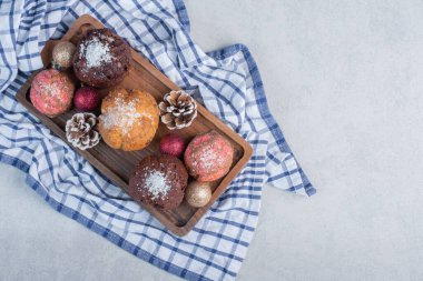 Çam kozalaklarıyla süslenmiş bir havlunun üzerindeki tatlı tepsisi ve mermer arka planda noel süsleri. Yüksek kalite fotoğraf