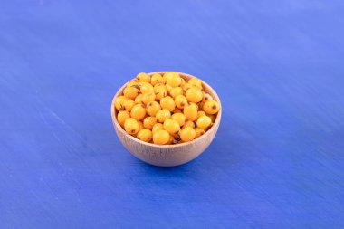 Mavi arka planda sarı kiraz dolu küçük bir ahşap kase. Yüksek kalite fotoğraf