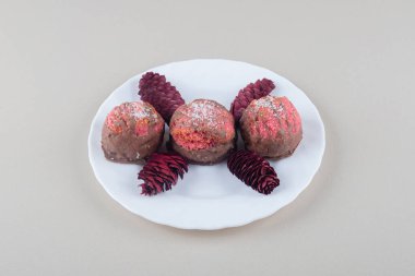 Küçük kekler ve kırmızı kozalaklar mermer bir tabakta. Yüksek kalite fotoğraf