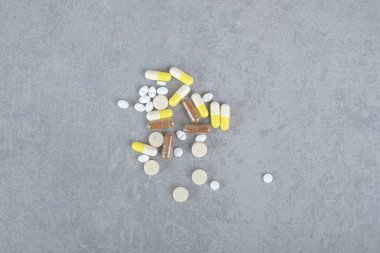 Gri arka planda çeşitli ilaç tabletleri ve kapsüller var. Yüksek kalite fotoğraf