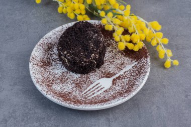 Beyaz tabakta sarı çiçekli bir dilim çikolatalı pasta. Yüksek kalite fotoğraf