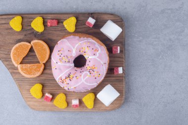 Marşmelovlar, marmelatlar ve mermer zemin üzerinde tahta bir tahtanın üzerinde bir çörek. Yüksek kalite fotoğraf