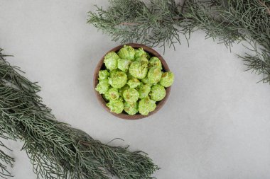 Dekoratif dallar mermer arka planda bir kase şekerli patlamış mısırı çevrelemiş. Yüksek kalite fotoğraf