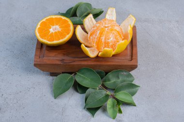 Mermer zemin üzerinde küçük bir tahta üzerinde soyulmuş ve dilimlenmiş mandalinalar. Yüksek kalite fotoğraf