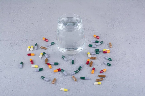Çeşitli ilaç kapsülleri ve bir bardak su. Yüksek kalite fotoğraf