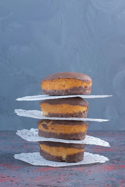 A stack of chocolate coated cakes and doilies on abstract background. High quality photo