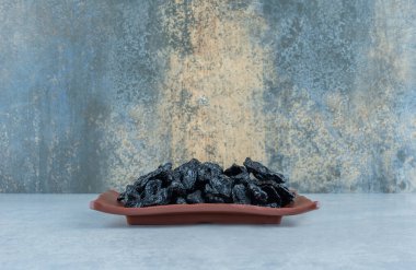 Mavi arka planda ahşap bir tabakta kurumuş ekşi kirazlar. Yüksek kalite fotoğraf