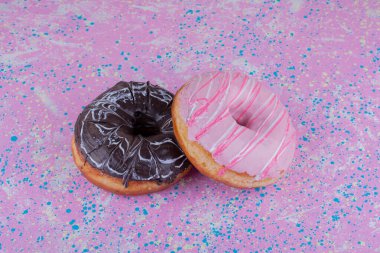 Arka planda pembe ve çikolata kremalı çörekler. Yüksek kalite fotoğraf