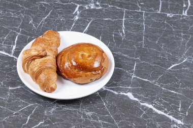 Ekmek ve çikolatalı kruvasan tabakta, mermer arka planda. Yüksek kalite fotoğraf