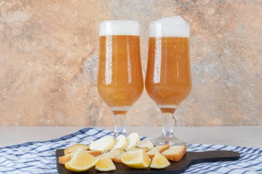 Koyu tahtada iki birayla çeşitli peynir ve limon dilimleri. Yüksek kalite fotoğraf