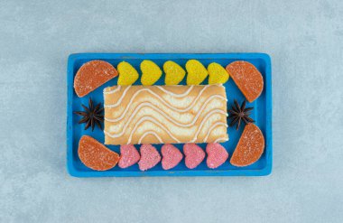 Kek rulosuyla mavi tabak ve mermer arka planda marmelat parçaları. Yüksek kalite fotoğraf