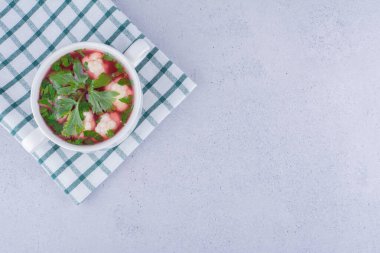 Mermer zemin üzerinde katlanmış masa örtüsü üzerinde küçük bir kâse içinde karnabahar çorbası servisi. Yüksek kalite fotoğraf