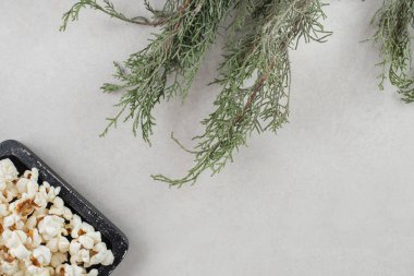 Tahta tepside patlamış mısır mermer arka planda ağaç dallarının yanına yerleştirilmiş. Yüksek kalite fotoğraf