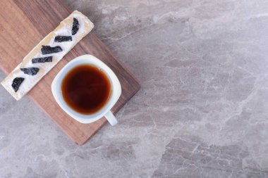 Gevrek ekmeğin üzerinde dilimlenmiş erik ve mermer zemin üzerinde, tahta tahtanın üzerinde bir fincan çay. Yüksek kalite fotoğraf