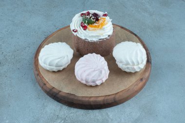 Küçük kek ve kurabiyeler mermer arka planda bir tahtaya yerleştirilmiş. Yüksek kalite fotoğraf