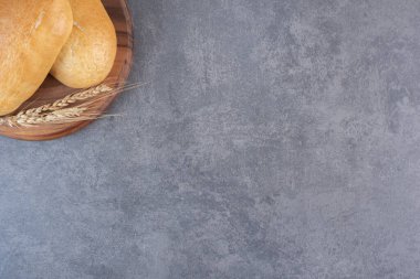 Çörekler ve tahtanın üzerinde mermer zemin üzerinde tek bir buğday sapı. Yüksek kalite fotoğraf